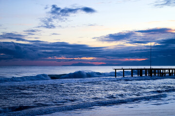 Obraz premium View from beach to water of sea, waves with white foam, pierce and sky with clouds in a nice evening.