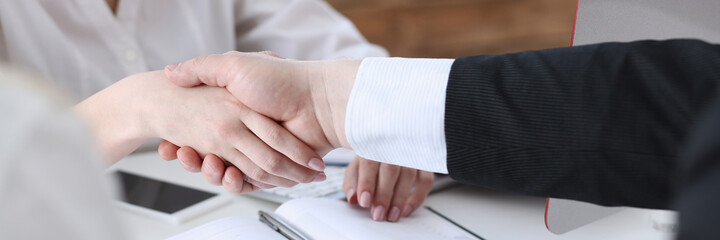 Businessman and woman shake hands as hello in office