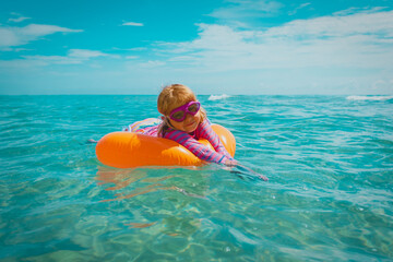 cute happy little girl swimming on floatie at tropical beach