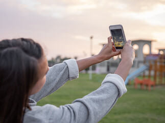 The girl photographs the sunset on a mobile phone.