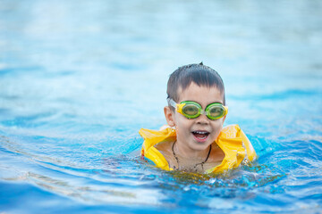 Naklejka premium smiling little boy swims in the pool