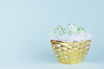 Fototapeta na wymiar Festive easter background - blue easter eggs with golden glitter dots in golden bowl on blue backdrop.