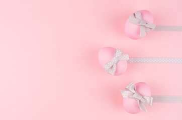 Cute easter eggs with grey ribbon in row as border on pastel pink background, copy space.