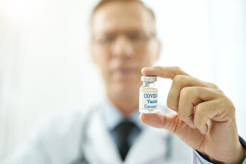 Male doctor holding bottle of coronavirus vaccine