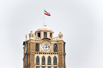 Fototapeta na wymiar Tabriz, Iran - December 19, 2015: Flag of Iran placed on top of the Clock Tower at Saat Square in Tabriz, Iran