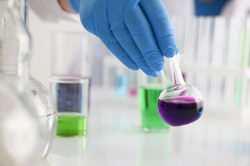 A male chemist holds test tube of glass in his hand overflows