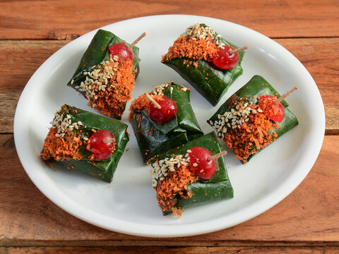 Rajwadi masala paan, Indian Traditional Mouth Freshener wrapped in betel leaf, often used as an after dinner digestive. served over a white plate on a rustic wooden background, selective focus
