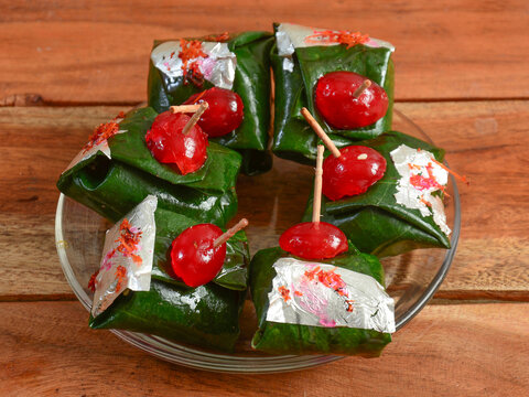Shahi kolkatta paan, Indian Traditional Mouth Freshener wrapped in betel leaf, often used as an after dinner digestive. served over a white plate on a rustic wooden background, selective focus