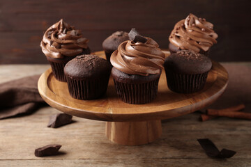 Delicious chocolate muffins and cupcakes decorated with cream on wooden table