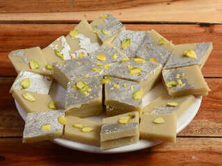 Kaju katli traditional indian sweet,served over a white plate on a rustic wooden background, selective focus