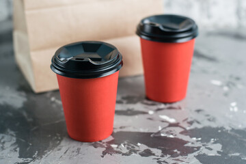 Two paper cups for tea or coffee to go and takeaway craft bag on gray background copy space. Concept for the development of the restaurant business and food delivery during quarantine covid 19