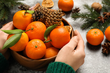 Fototapeta na wymiar Woman with fresh tangerines at table, closeup. Christmas atmosphere