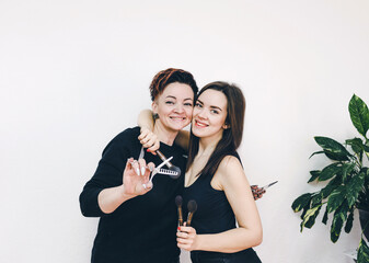 two girls a hairdresser and a makeup artist embrace each other