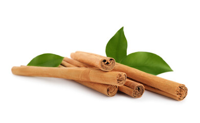 Aromatic dry cinnamon sticks and green leaves on white background