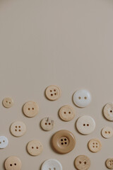 Buttons pattern on neutral beige background. Flat lay, top view. Minimalistic sewing concept.