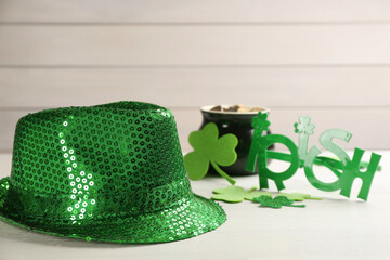 Green sequin hat, decorative clover leaves and party glasses on white wooden table. St Patrick's...