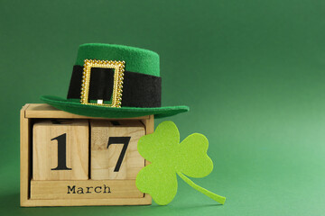 Leprechaun's hat, block calendar and St. Patrick's day decor on green background. Space for text