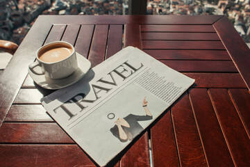 cup of coffee and travel newspaper on wooden table in cafe