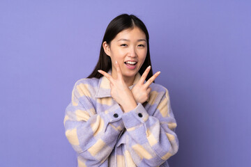 Young asian woman isolated on purple background smiling and showing victory sign