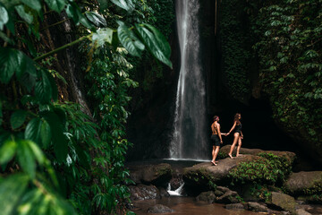 A couple in love on a waterfall. Honeymoon trip. Happy couple on the island of Bali. Beautiful couple travels the world. Travel to Indonesia. Happy couple on vacation.  Wedding trip. Copy space