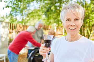 Elderly woman with glass of wine at a garden party