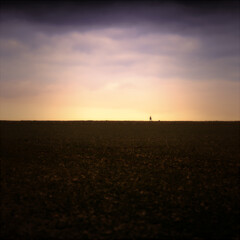 A landscape photo on a mountain at sunset with a walker and his dog on top of the ridge as an outline