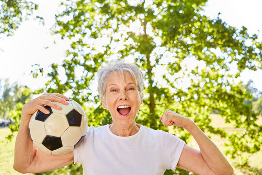 Vital elderly woman with soccer ball cheers after a game