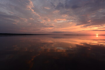 Fototapeta na wymiar sun setting on the horizon above the water surface lake