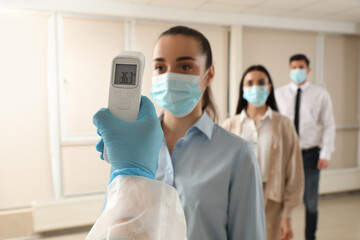 Fototapeta na wymiar Doctor measuring employees temperature in office, closeup. Prevent spreading of Covid-19