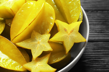 Delicious carambola fruits on black wooden table, closeup