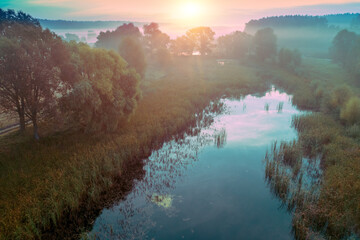 Early misty morning, sunrise over lake. Rural landscape in summer. Aerial view