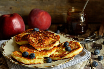 Cheesecake pancakes with blueberries on a rustic plate on a wooden background