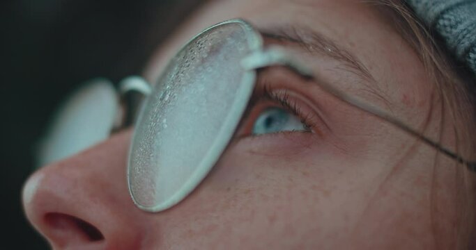 Beautiful young woman with deep bright blue eyes look up at sky through fogged glasses. Romantic inspiring stare. Millennial female adventurer, meditative and contemplative. Mindfulness concept
