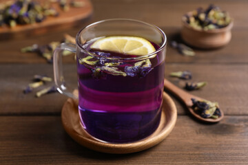 Glass mug of organic blue Anchan with lemon on wooden table. Herbal tea