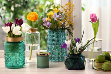 Different beautiful spring flowers and candle on window sill