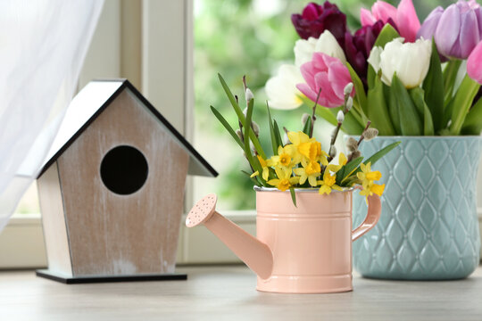 Beautiful spring flowers with birdhouse on window sill