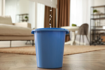 Bucket collecting water from ceiling in living room. Leaking roof © New Africa