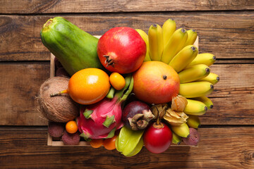 Crate with different exotic fruits on wooden table, top view