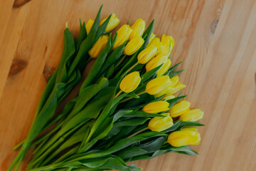 Bright fresh yellow tulips on wooden background. Many yellow tulips on wooden table. Bunch of flowers on the table.