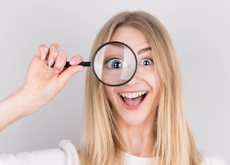Close up portrait of cheerful beautiful girl looking through magnifying glass isolated on white background