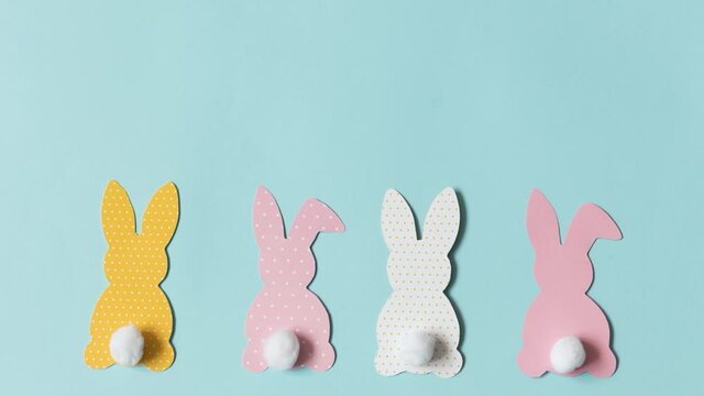 Stop motion video, easter paper colorful bunnies on blue background. High quality 4k footage
