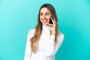 Fototapeta premium Young caucasian woman using mobile phone isolated on blue background looking side