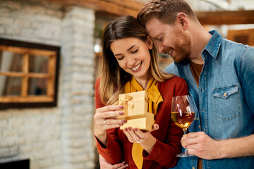 Young happy woman opening gift she has received from her boyfriend for their anniversary.