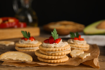 Delicious crackers with humus, bell pepper and parsley on wooden table