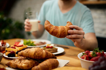 Obraz na płótnie Canvas Close-up of man having croissant for breakfast.