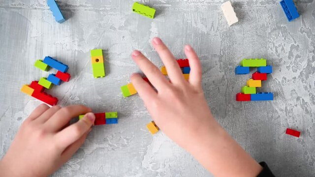 close-up kids hands building numbers 2022 from colorful constructor blocks on isolated gray background