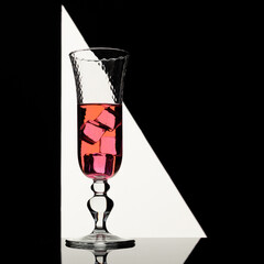 Pink drink in elegant glass with ice cubes backlit in 
geometric shaped light