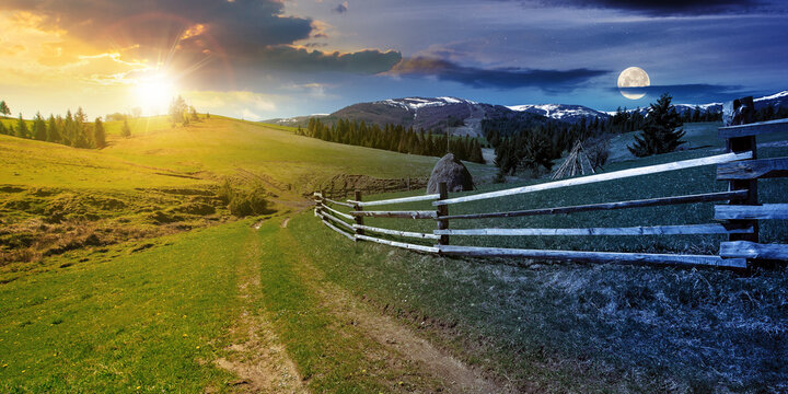 day and night time change concept above rural landscape in spring. path through grassy field. wooden fence on rolling hills. snow capped ridge in the distance. wonderful countryside with sun and moon