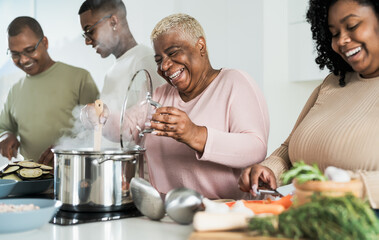 Happy black family having fun cooking together in modern kitchen - Food and parents unity concept