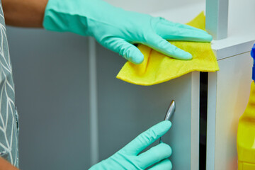 Bearded man cleaning home table surface with towel and gloves, disinfectant spray bottle